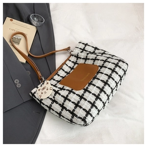 Detail of checkered tote bag with brown leather pocket and cute white cat pendant