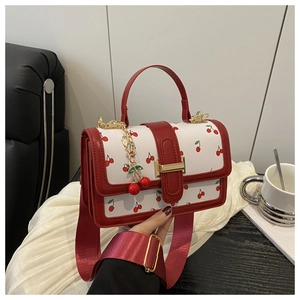Detail of cherry print handbag with 3D cherry charm and golden metal buckle closure