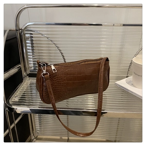 Close-up of dark brown crocodile embossed shoulder bag with silver zipper and buckle detail