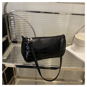 Close-up of black crocodile pattern faux leather shoulder bag with silver hardware and zipper