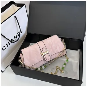 Detail of pink pleated texture bag with golden buckle and beaded chain strap