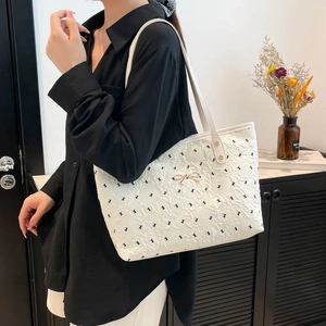Quilted tote bag with rabbit patterns and metal bow detail shown on a shoulder