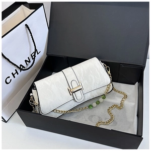 Detailed shot of white marble textured bag with golden buckle and beaded metal chain strap