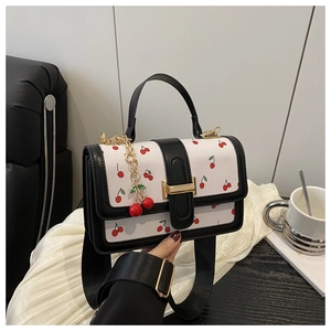 Detail of cherry print handbag with golden clasp and matching cherry metal pendant charm
