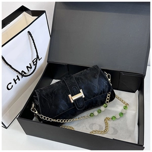 Detail of black pleated shoulder bag with golden H-buckle and beaded chain in a gift box