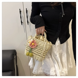 Detail of hollow woven straw bag featuring floral cherry charms and drawstring inner lining