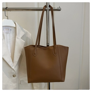 Close-up of brown minimalist tote bag with long handles hanging on a metal rack