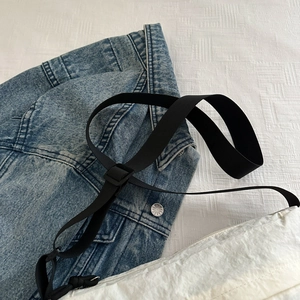 Detail of white pleated shoulder bag with adjustable strap and washed denim fabric