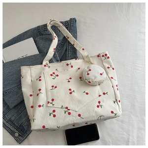 Detail of white corduroy tote bag featuring red cherry prints and matching coin purse