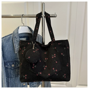 Detail of black corduroy tote bag with red cherry embroidery and round coin purse