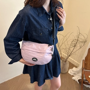 Detail of light purple pleated crescent bag with black Lucky Fashion logo and wide strap