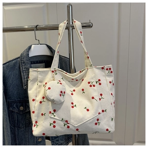 Detail of white corduroy tote bag with cherry prints and a mini round coin purse charm