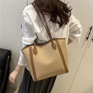 Minimalist beige tote bag with brown straps shown on shoulder for a stylish casual look