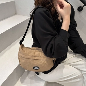 Detail of khaki crescent nylon bag with adjustable black strap and brand logo