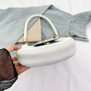 Detail of white cross-grain leather bag with black flap and gold hardware