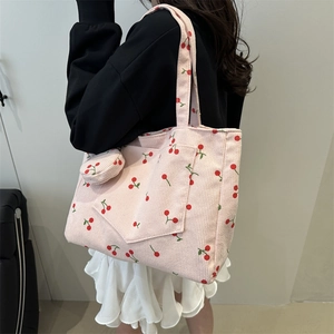 Pink corduroy tote bag with cherry print and matching mini coin purse on shoulder