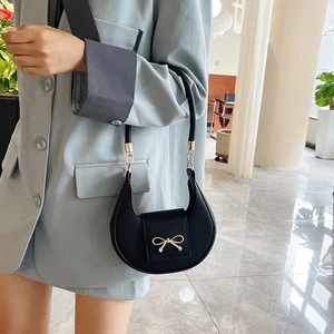 Borsa a spalla a mezzaluna nera con fiocco dorato indossata da una modella