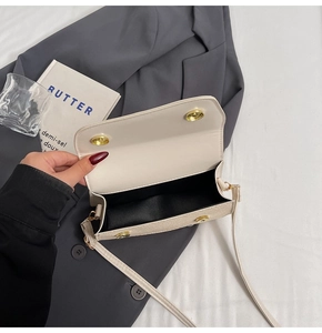 Detail view of cream crossbody bag interior with dual gold magnetic closures and black lining
