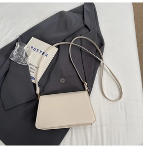 Close-up of cream white leather flap bag on a grey suit with minimalist aesthetic