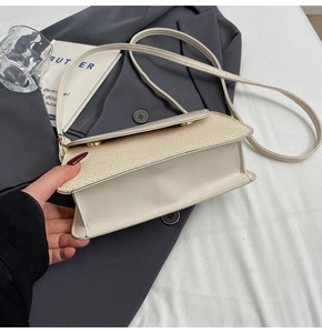 Detail of off-white crossbody bag featuring straw patchwork and gold snap fasteners