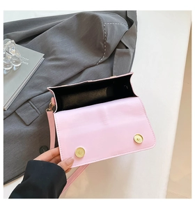 Detail van de roze handtas met gouden magneetsluitingen en zwarte binnenvoering