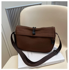 Detailansicht der braunen Canvas-Tasche mit Doppelreißverschluss auf weißem Stuhl