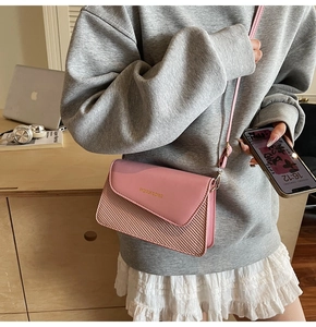Close-up of pink crossbody bag with woven texture and gold fashion logo detail