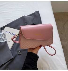 Detail of pink PU leather crossbody bag with woven texture and gold fashion logo