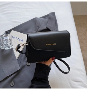 Detail of black leather crossbody bag featuring a textured finish and gold logo