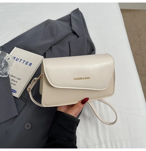 Detail of cream white crossbody bag featuring leather stitching and woven texture pattern