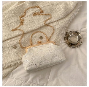 Close-up of white lace handbag with silver sequins and gold carved metal handle