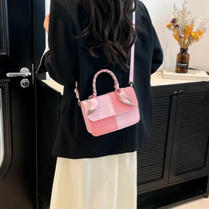 Pink patchwork handbag with scarf-wrapped handle and gold hardware on black blazer