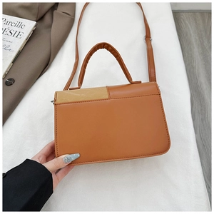 Close-up of brown patchwork PU leather handbag with top handle and shoulder strap
