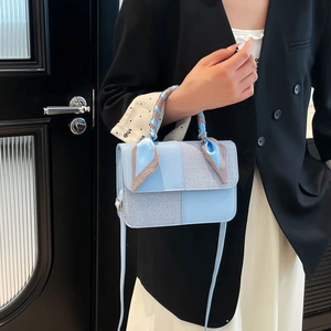 Chic light blue patchwork handbag with silk scarf handle held by a model