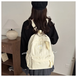 Detailed back view of cream nylon backpack with yellow smiley face and drawstring pockets