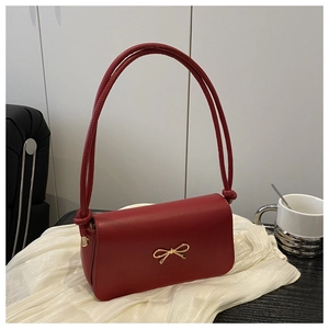 Détail du sac à bandoulière en similicuir rouge avec un fermoir nœud en métal doré