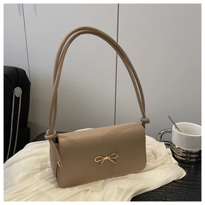 Vue détaillée du sac baguette kaki avec boucle nœud doré sur fond en tissu de soie