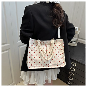 Detail of off-white corduroy tote bag with red heart pattern and dual front pockets