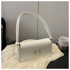Gros plan du sac à main en cuir blanc avec boucle nœud doré sur tissu de soie
