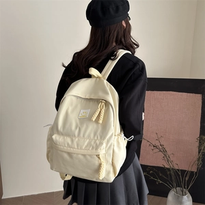 Minimalist cream college backpack with yellow smiley patch and rope zipper pullers
