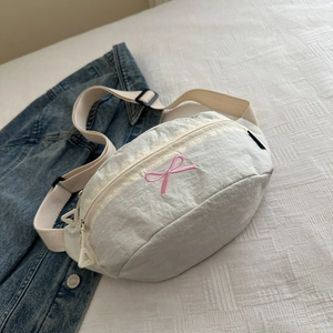 Détail du sac croissant crème avec broderie nœud rose et texture en nylon léger