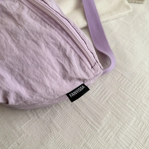 Gros plan du sac cabas en nylon lilas avec fermeture éclair et étiquette de marque noire