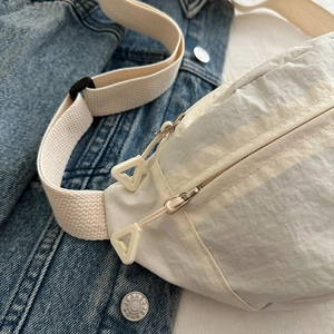 Détail du sac bandoulière en nylon crème avec double fermeture éclair et tirettes