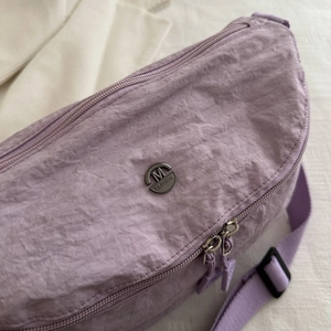 Détail macro du tissu en nylon plissé violet avec un logo métallique rond M FASHION