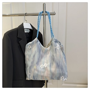 Detail of floral tote bag featuring 3D white flower appliques and woven rope handle