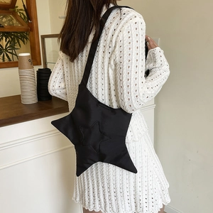 Sac bandoulière noir en forme d'étoile avec matelassage porté par un mannequin en robe