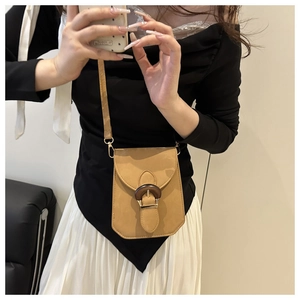 Détail d'un mini sac bandoulière camel avec une boucle texturée effet grain de bois