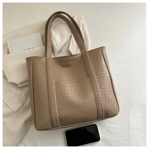 Close-up of a large dark brown woven leather tote bag with stylish shoulder straps