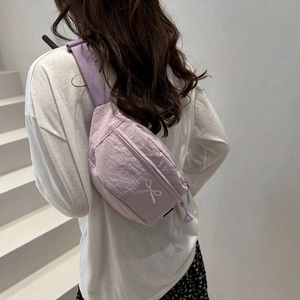 Détail du sac de poitrine en nylon lilas avec broderie nœud blanc et bandoulière réglable