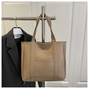 Detail shot of the woven texture and double handles on a khaki tote bag